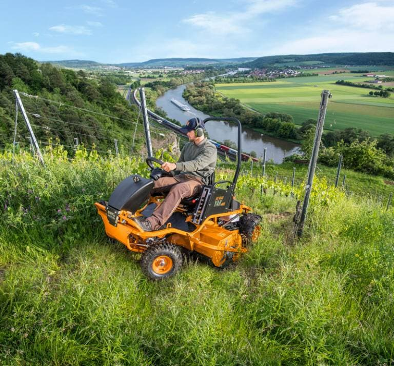 Mann bedient AS 1040 YAK 4WD Aufsitzschlegelmäher auf steiler Wiese