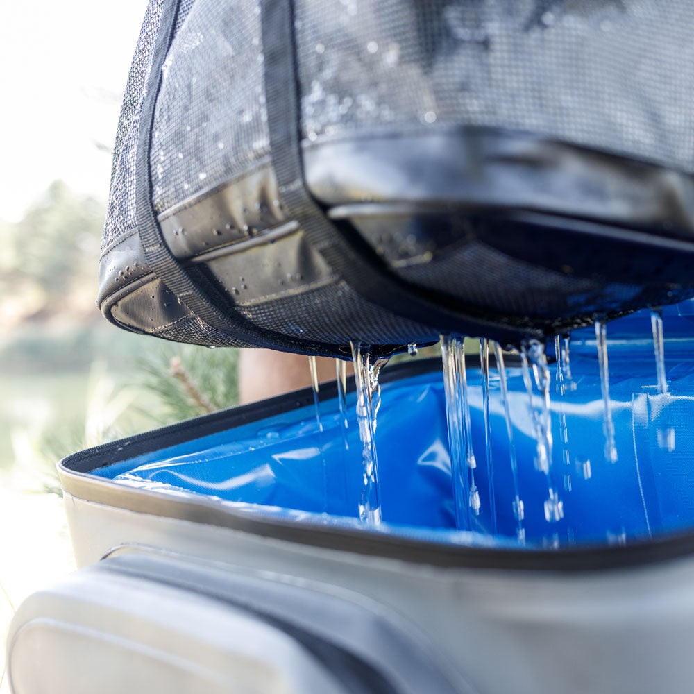 Wasserdichte Petromax Kühltasche tropft Wasser auf blauen Untergrund im Freien