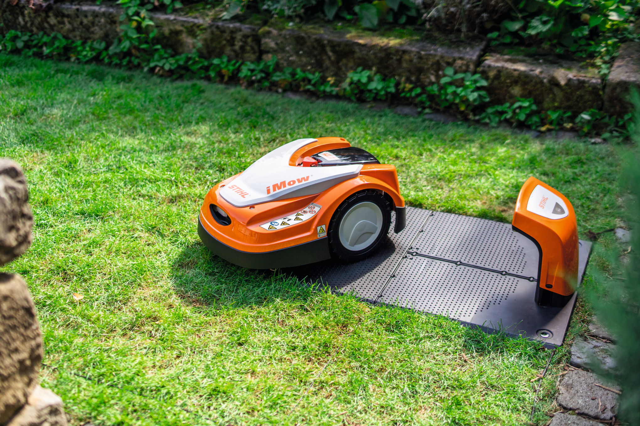 Stihl iMOW Mähroboter auf ADO 401 Dockingstation im grünen Garten