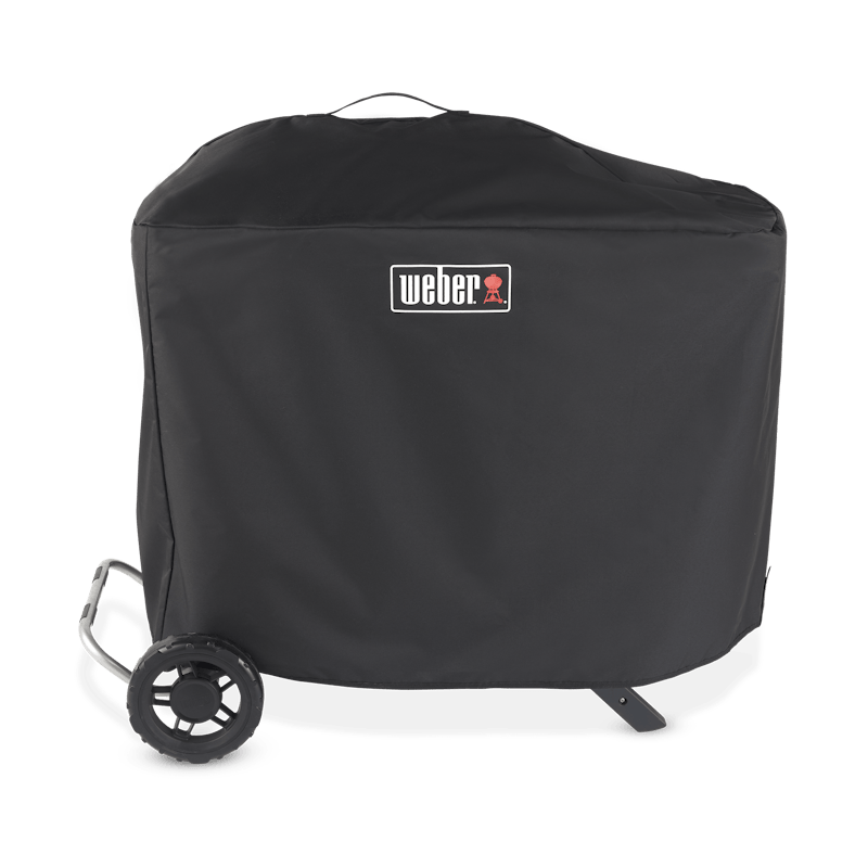 Schwarze Weber Traveler Premium Abdeckhaube über einem Grill mit sichtbarem Weber-Logo