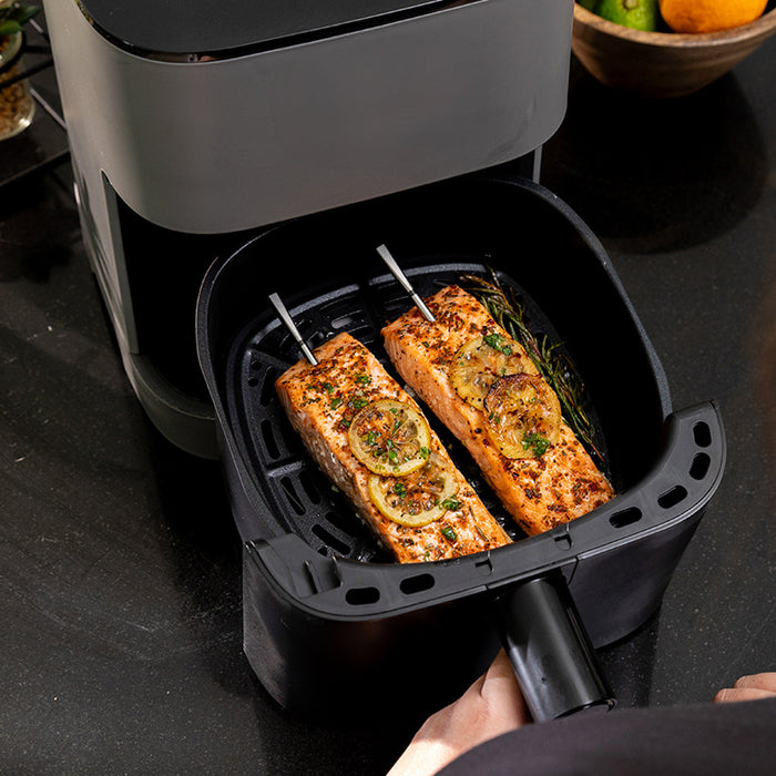 Moderne Küchentechnik MEATER Pro XL mit zwei Lachsfilets garniert mit Zitronen und Kräutern