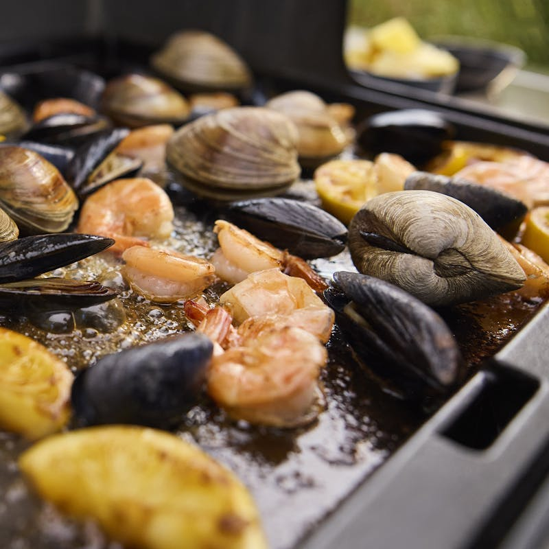 Meeresfrüchte und Zitronen auf einer Grillplatte des Weber Genesis Gasgrills