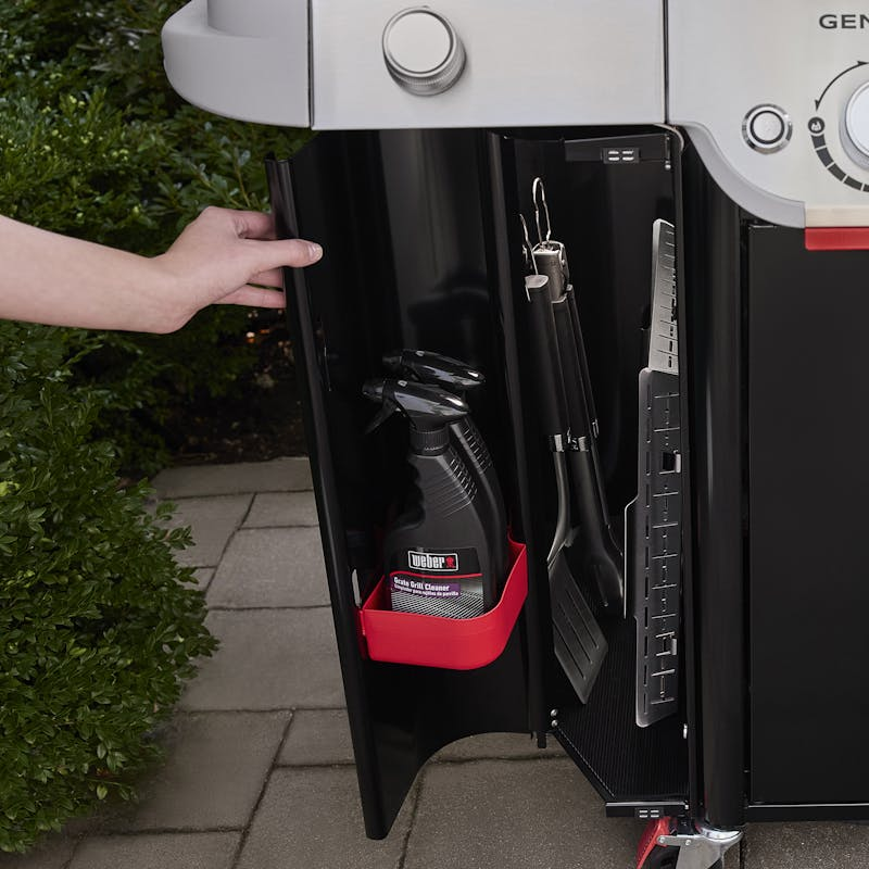 Hand öffnet Unterschrank eines Weber GENESIS SP-435W GBS Gasgrills mit Zubehör