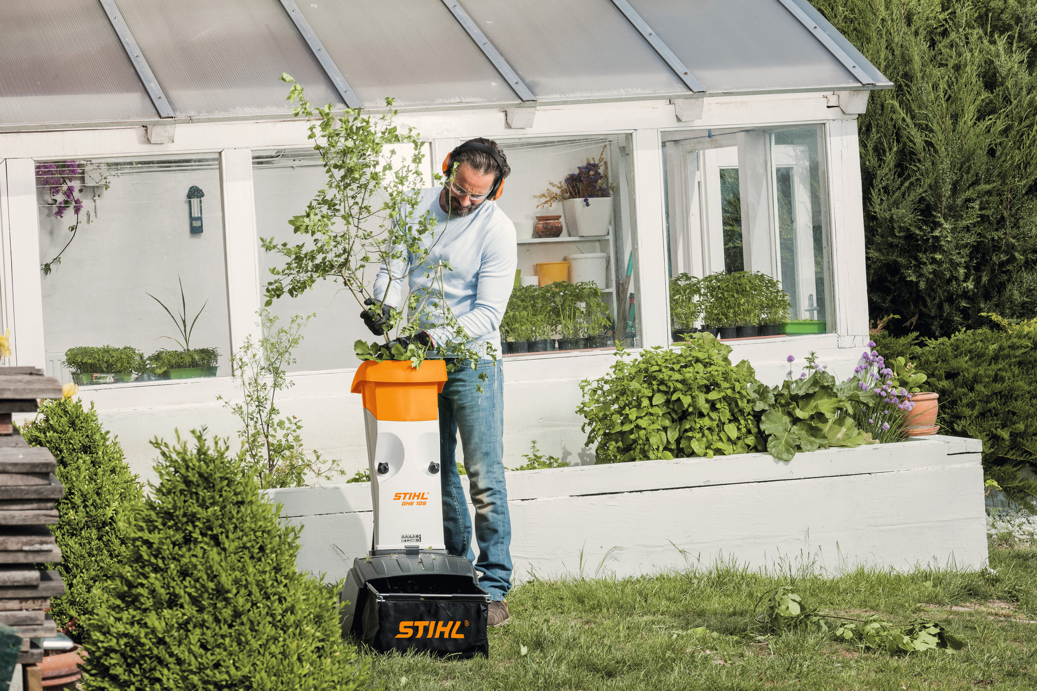 Mann verwendet STIHL Elektro-Häcksler GHE 105 im Garten