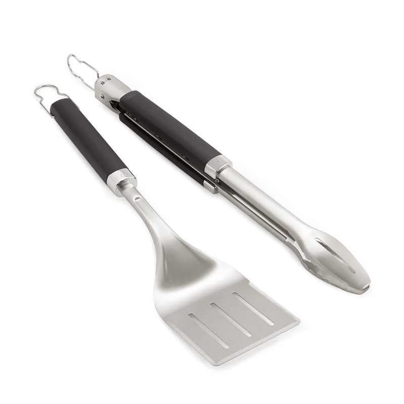 Weber Premium Grillbesteck-Set aus Edelstahl mit schwarzen Griffen auf grünem Hintergrund