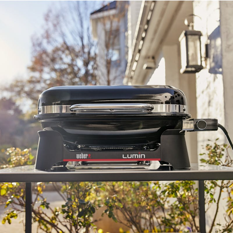 Weber LUMIN Elektrogrill auf einer Terrasse mit herbstlichem Hintergrund