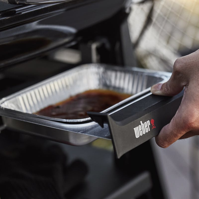 Hand entnimmt Grillsoße aus Weber Elektrogrill