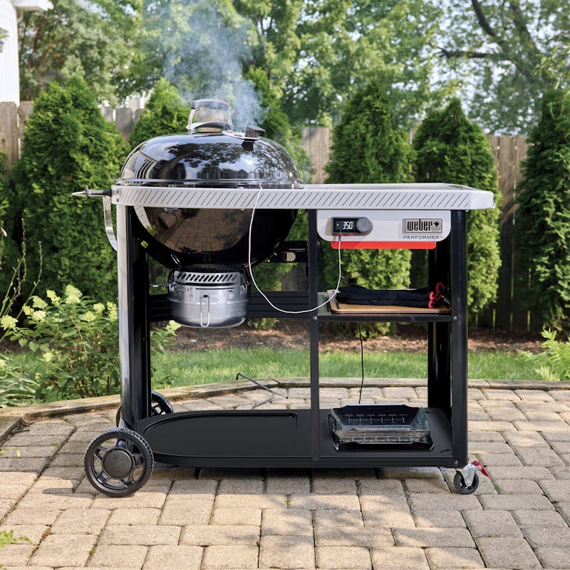 Weber Performer Premium Smart Holzkohlegrill im Garten mit Rauch und digitaler Temperaturanzeige