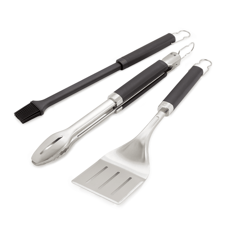 Weber Premium Grillbesteck-Set mit Zange Wender und Pinsel auf grünem Hintergrund