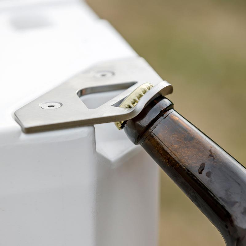 Petromax Schlossplatte mit Flaschenöffner an einer Kühlbox beim Öffnen einer Bierflasche