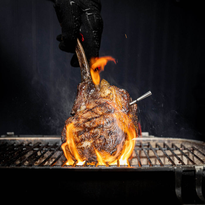 Tomahawk-Steak auf Grill mit MEATER Pro Thermometer und Flammen