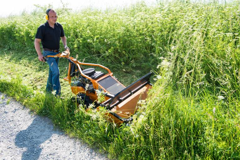 Mann bedient AS 901 SM Schlegelmulcher auf Weg neben hohem Gras