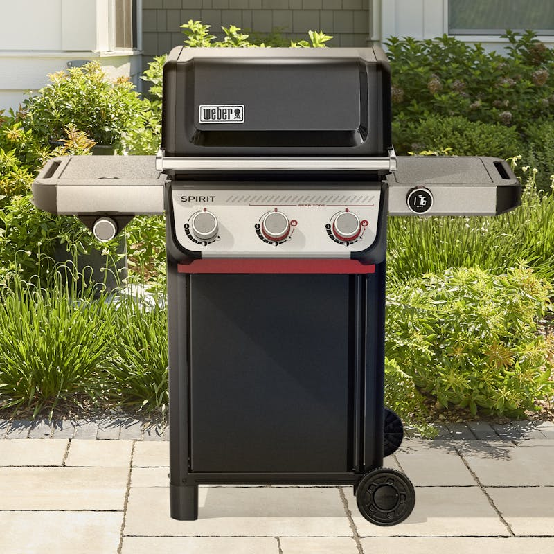 Weber SPIRIT EX-335 Gasgrill auf einer Terrasse mit geschlossener Haube und umgebender Vegetation