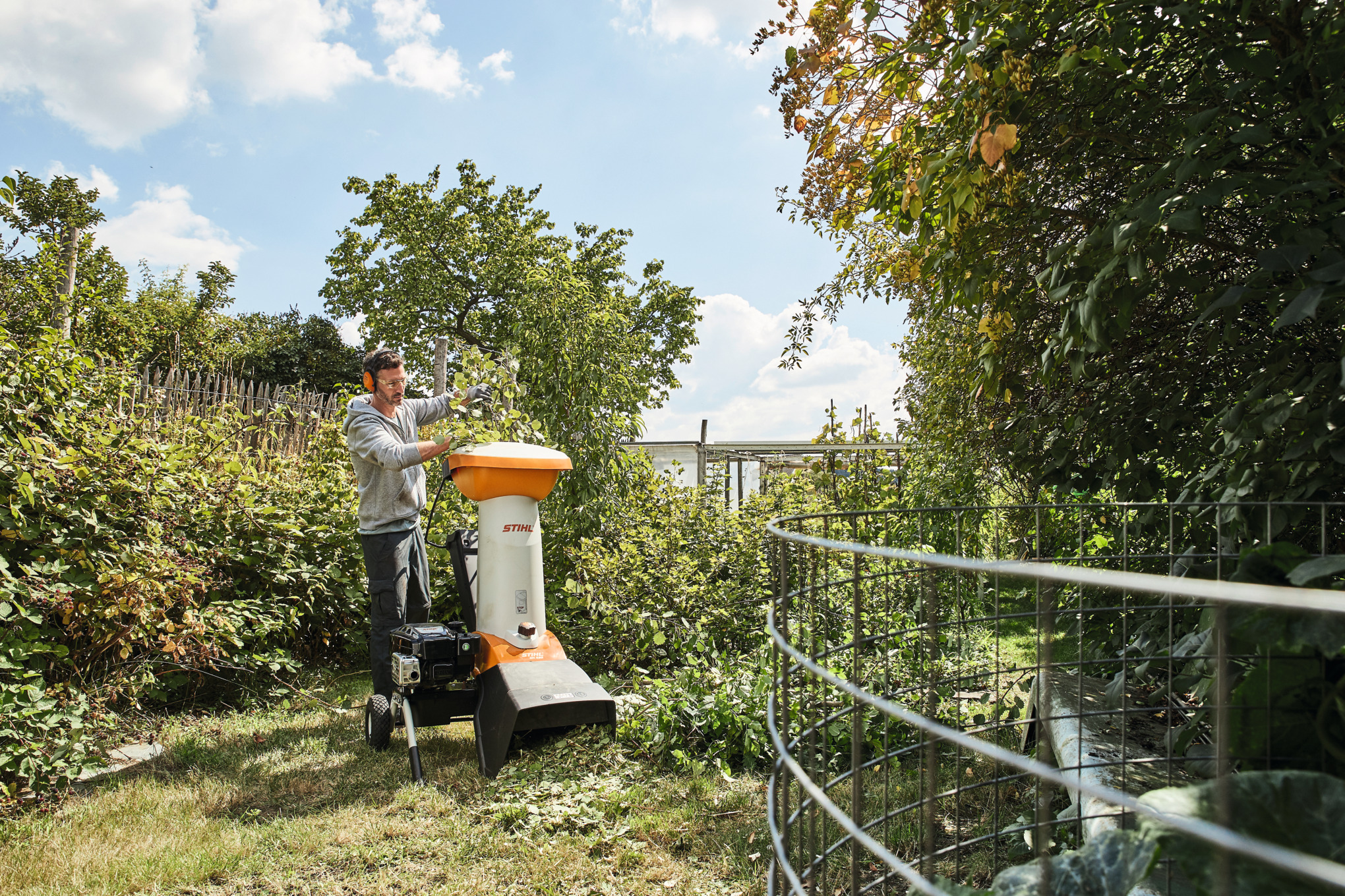 Mann verwendet STIHL GH 460 Häcksler in sonnigem Garten