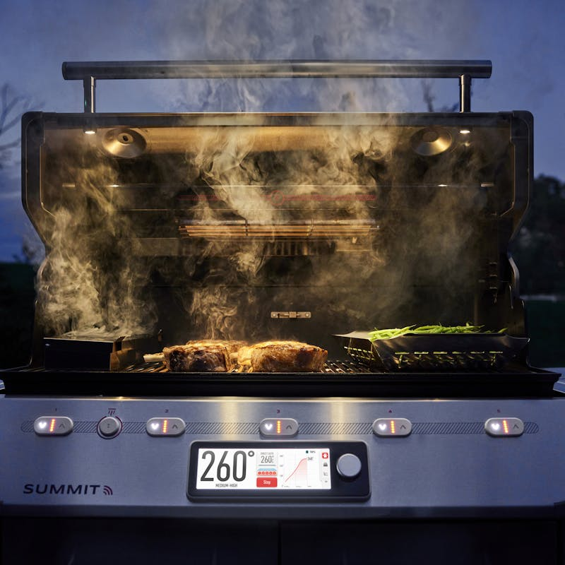 Weber Summit FS38X S Smart Grill in Betrieb mit Steaks und Spargel bei Abenddämmerung