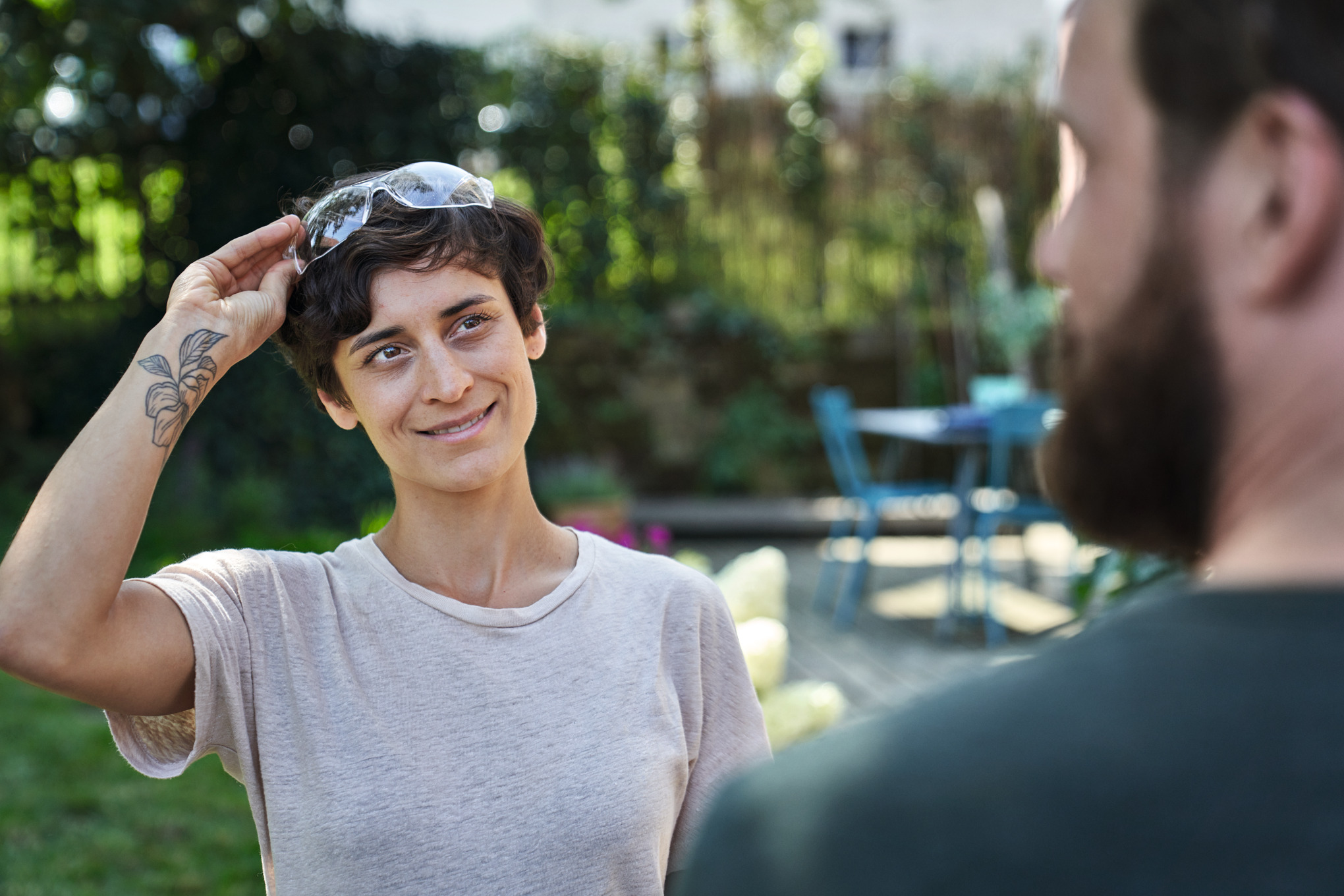 Frau mit STIHL Schutzbrille im Garten lächelt Mann an
