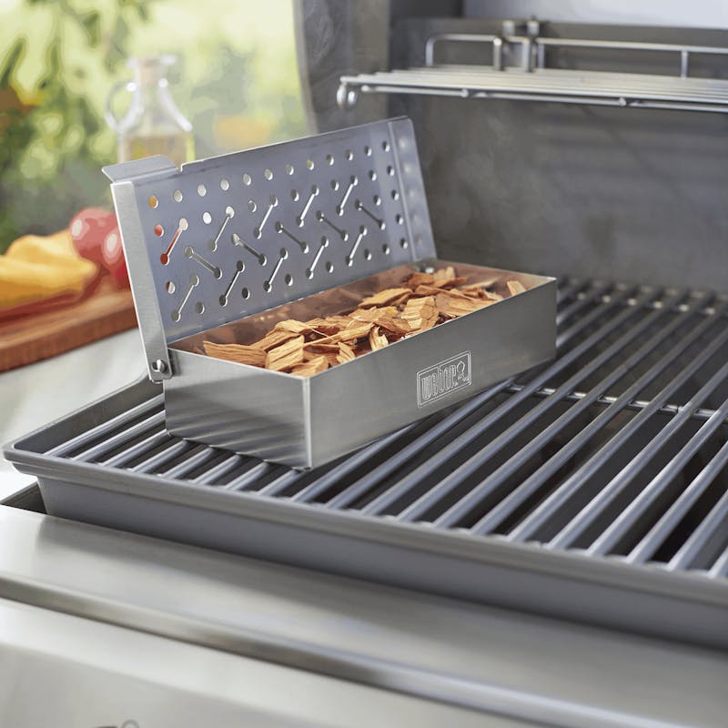 Weber Räucherbox aus Edelstahl gefüllt mit Holzchips auf einem Gasgrill