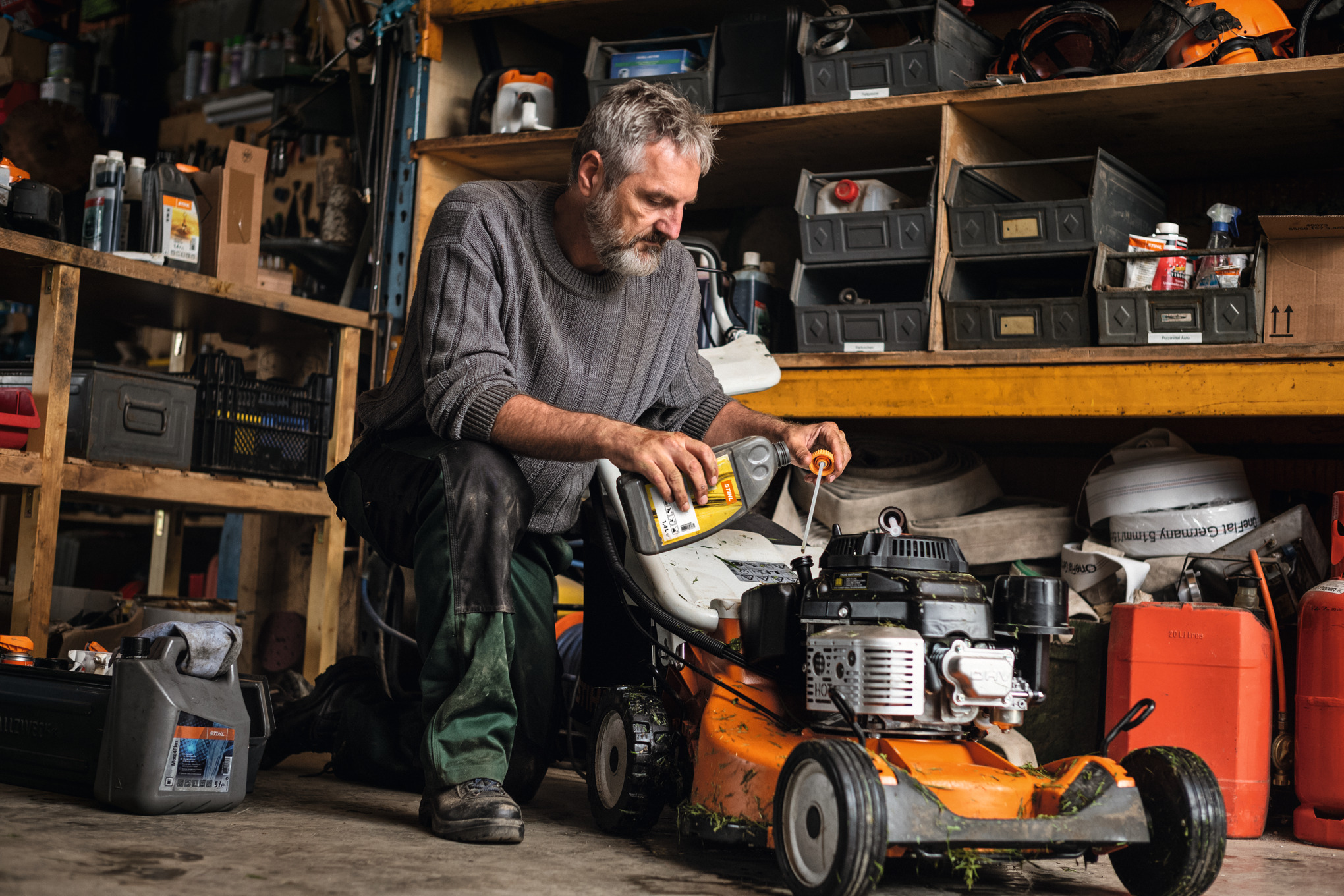 Älterer Mann wartet STIHL Rasenmäher in Werkstatt