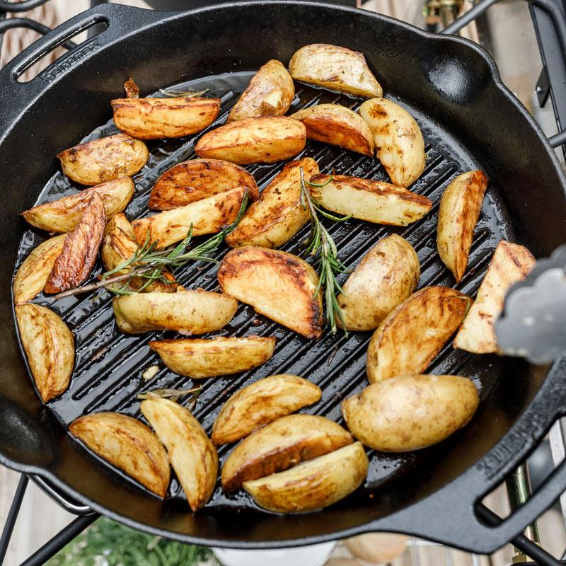 Petromax Grill-Feuerpfanne gp35h mit gebratenen Kartoffeln und Rosmarin auf einem Grill