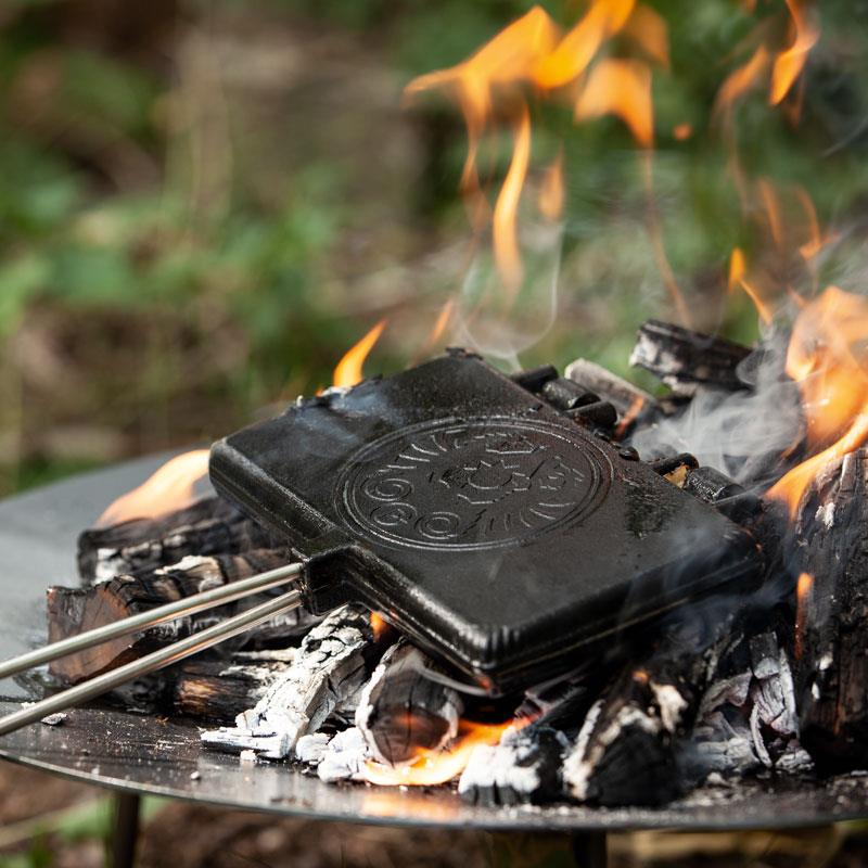 Petromax Waffeleisen auf einem Grill über offenem Feuer im Freien