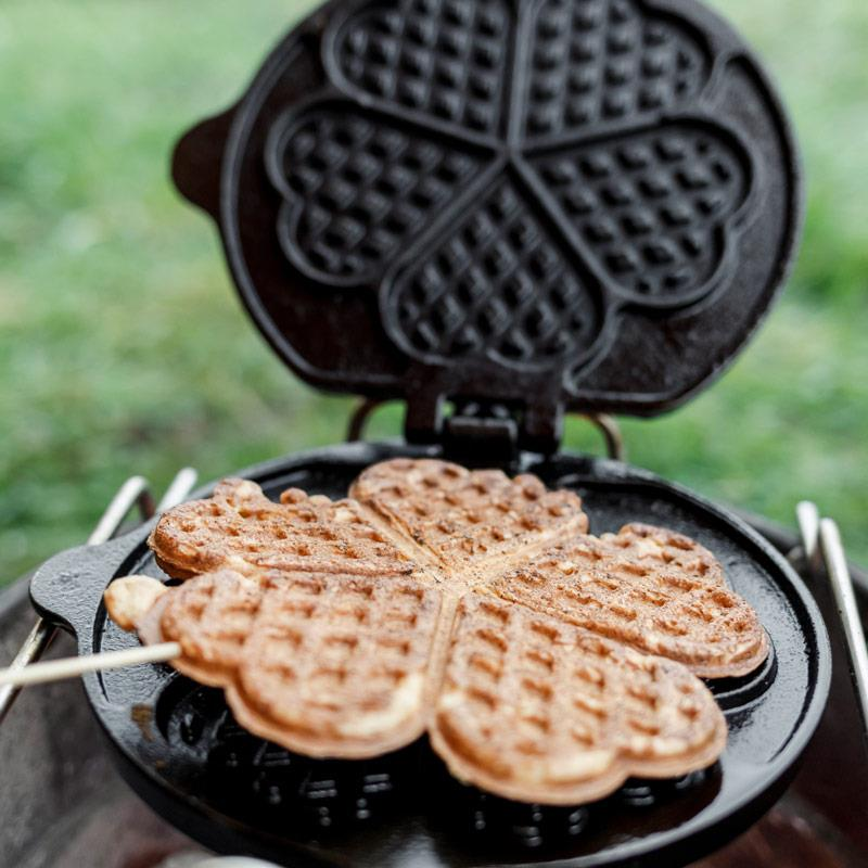 Petromax Waffeleisen mit zwei herzförmigen Waffeln auf einem Grill im Freien