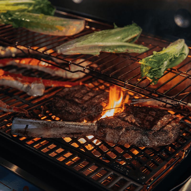 Steaks und Gemüse auf Weber CRAFTED Sear Grate mit sichtbaren Flammen