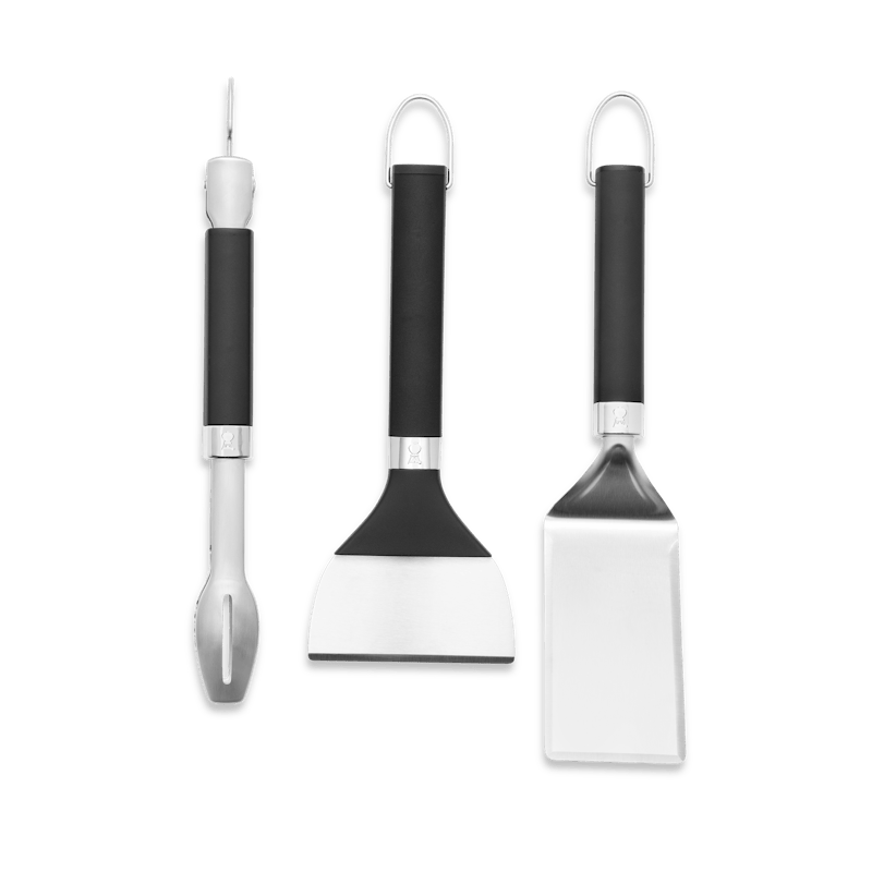 Weber Griddle Grillwerkzeug-Set mit Zange Wender Schaber vor grünem Hintergrund