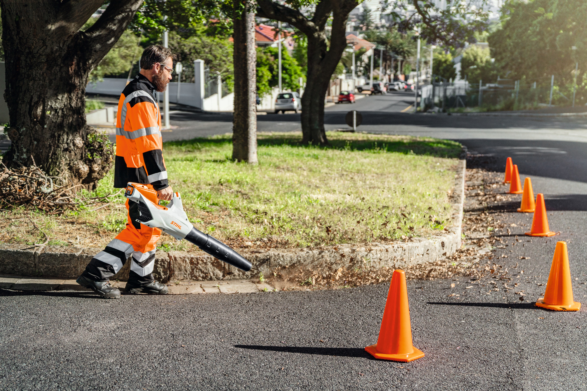 Mann in Sicherheitskleidung benutzt Stihl Akku-Laubbläser auf städtischer Straße