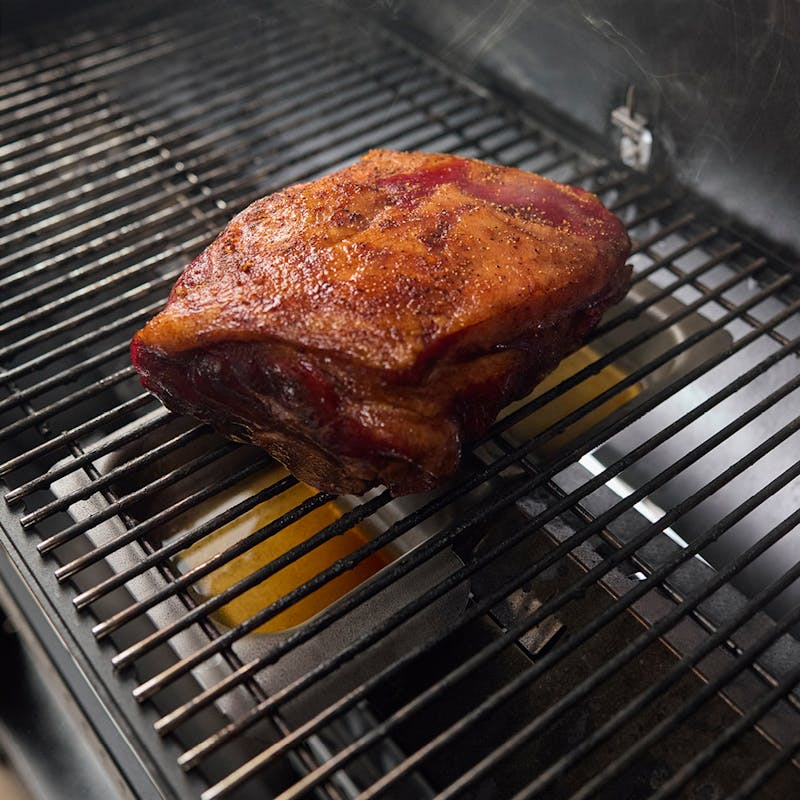 Gebräuntes Fleisch auf einem Grillrost mit Rauch, Einsatz des Weber Wet-Smoke-Sets
