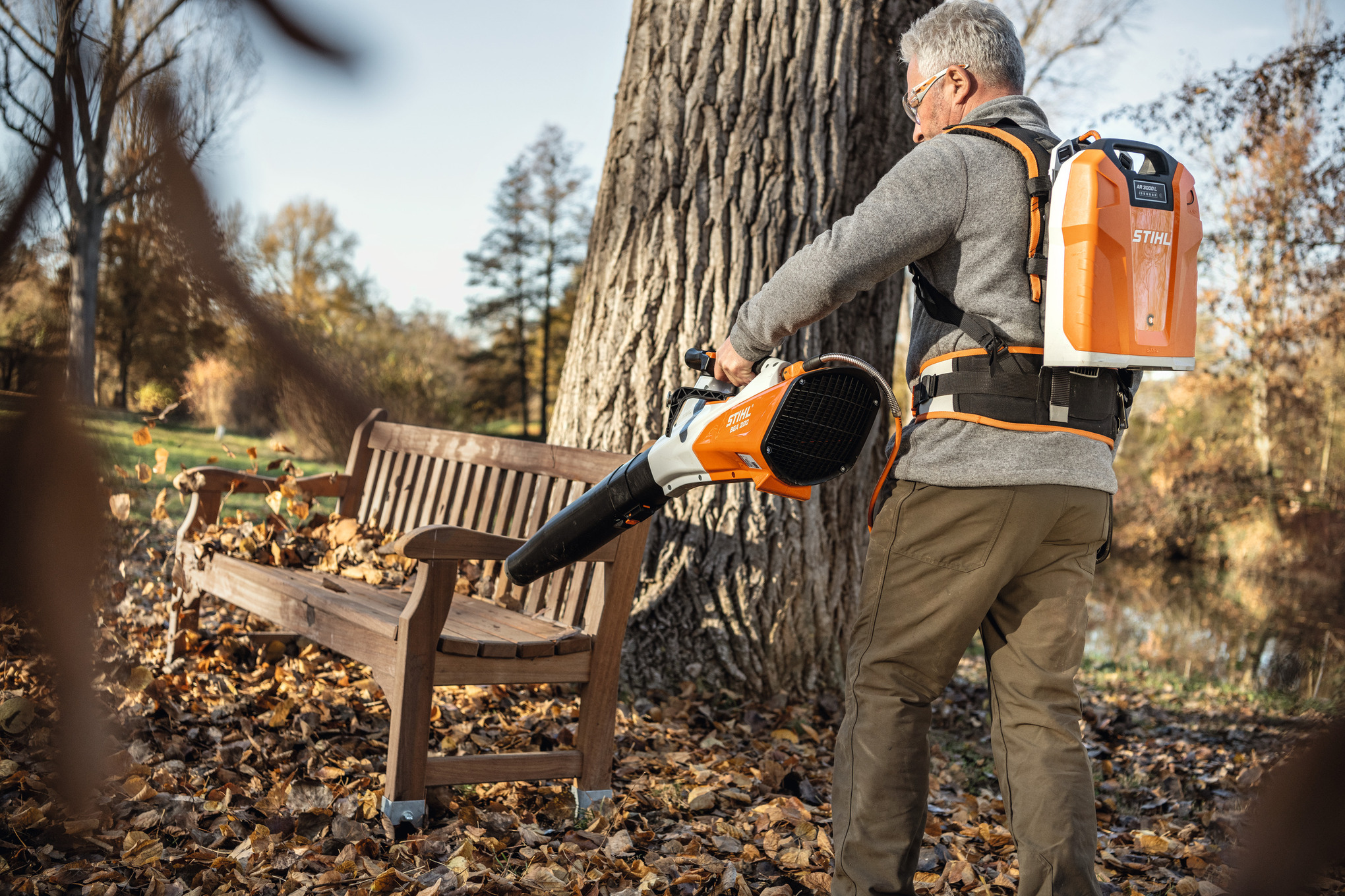 Älterer Mann verwendet STIHL BGA 200 Akku-Laubbläser in einem herbstlichen Park