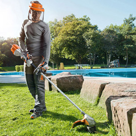 Person verwendet Stihl FSA 90 R Akku-Motorsense auf Rasen neben Pool