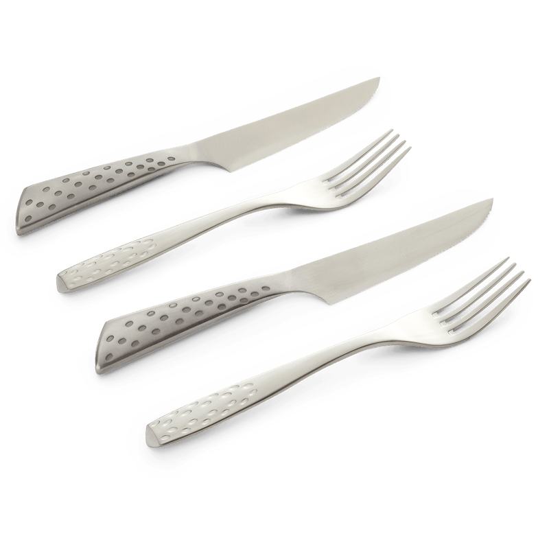 Weber Deluxe Steak-Set mit zwei Messern und zwei Gabeln auf dunkelgrünem Hintergrund