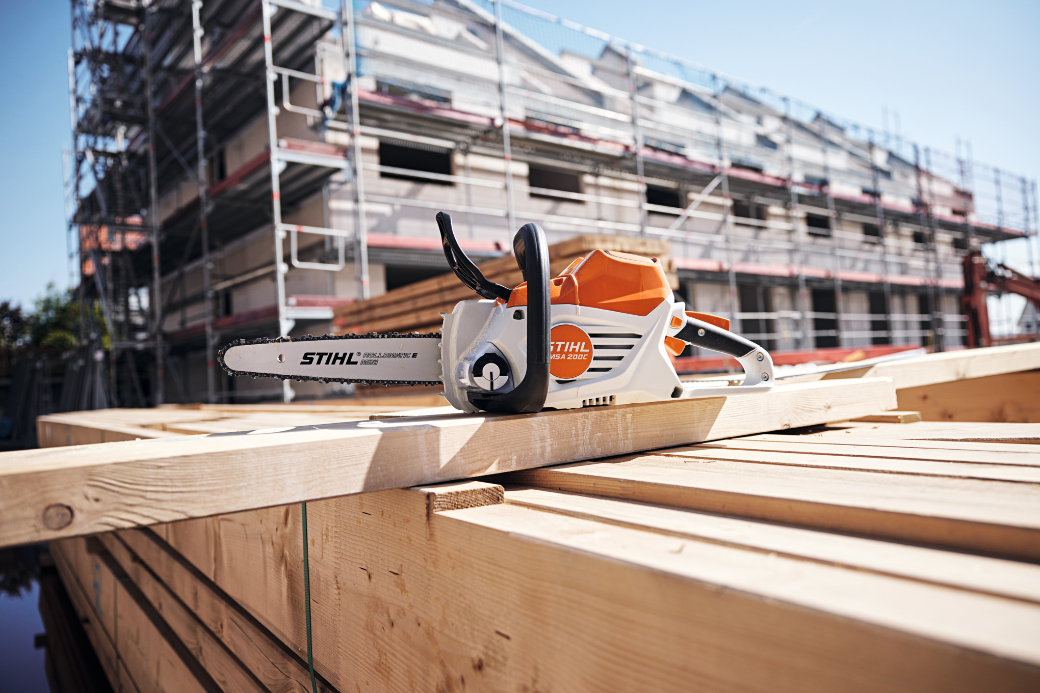 STIHL MSA 200 C-B Akku-Kettensäge auf Holzbrettern vor Baugerüst