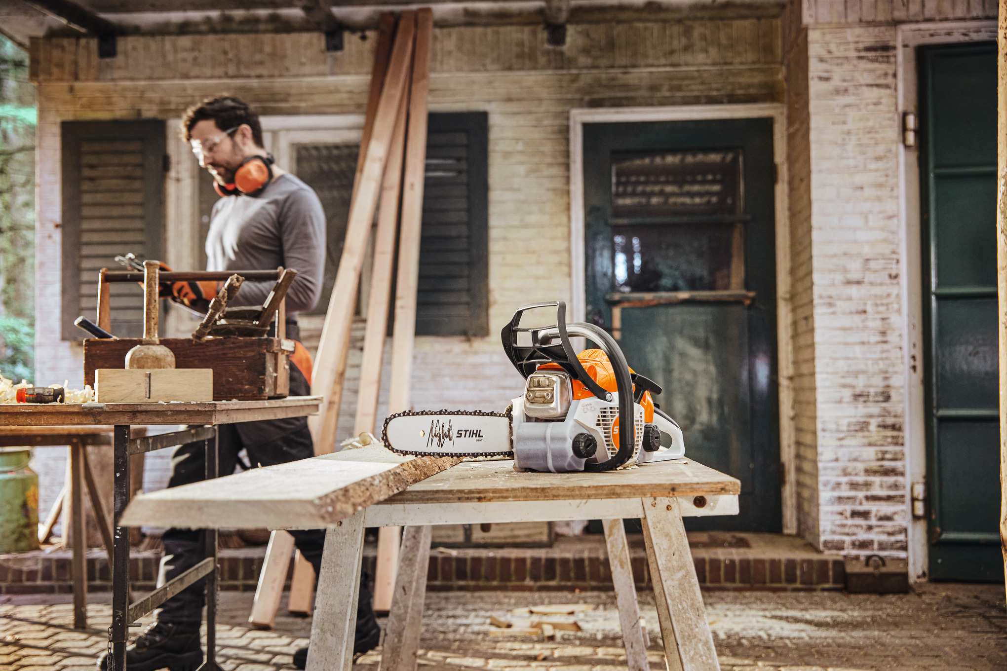Mann in Werkstatt arbeitet neben Stihl Benzin-Kettensäge
