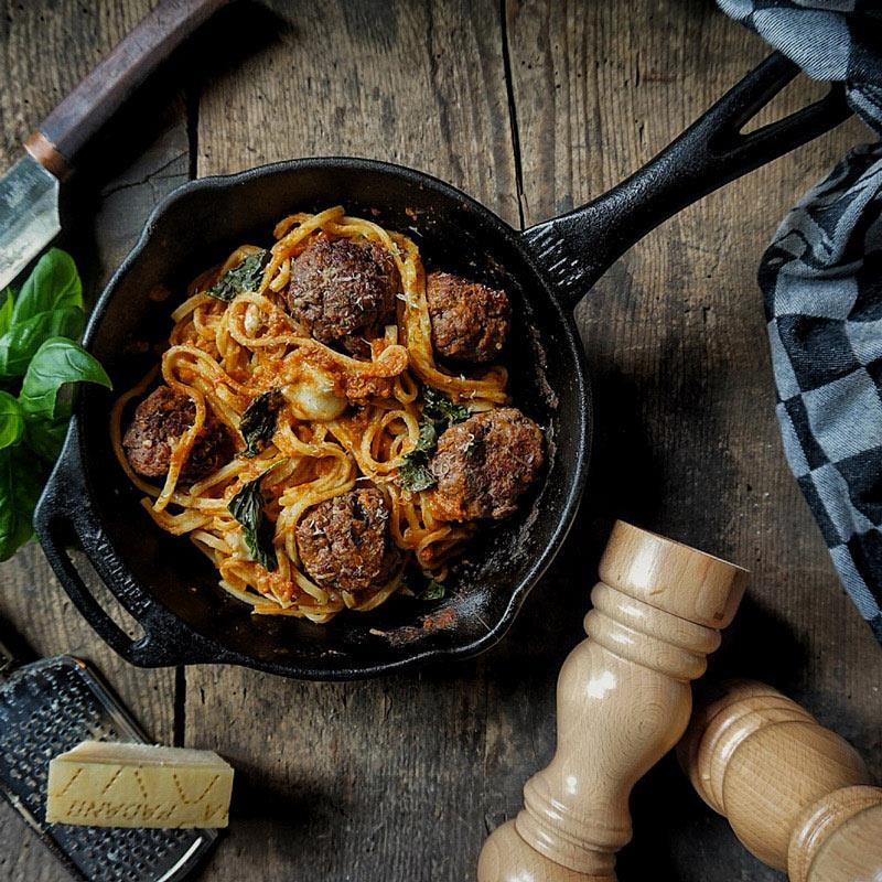 Petromax Feuerpfanne mit Spaghetti und Fleischbällchen auf Holztisch