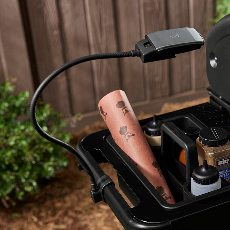 Flexible Weber WORKS Lampe angebracht an einem Grill zur Beleuchtung des Seitentischs