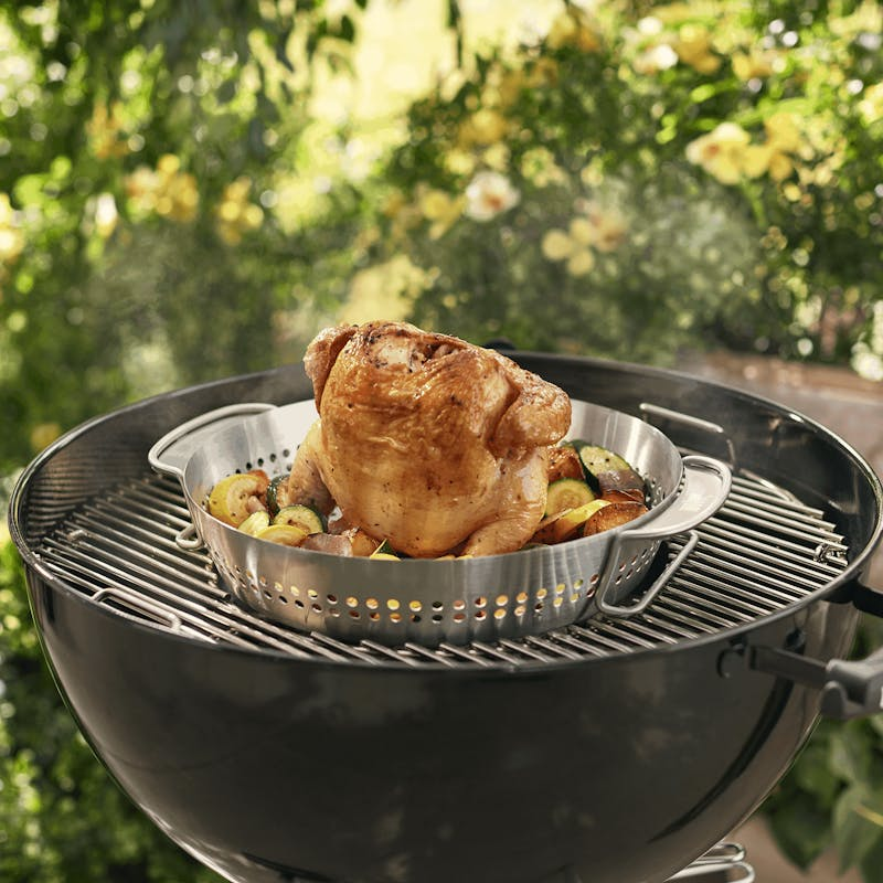 Knuspriges Hühnchen im Weber Gourmet BBQ System Geflügelbräter auf einem Grill umgeben von Gemüse