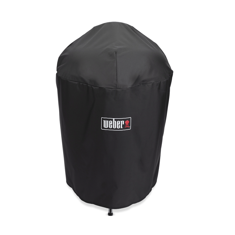 Schwarze Weber Premium Abdeckhaube für Holzkohlegrill auf grünem Hintergrund