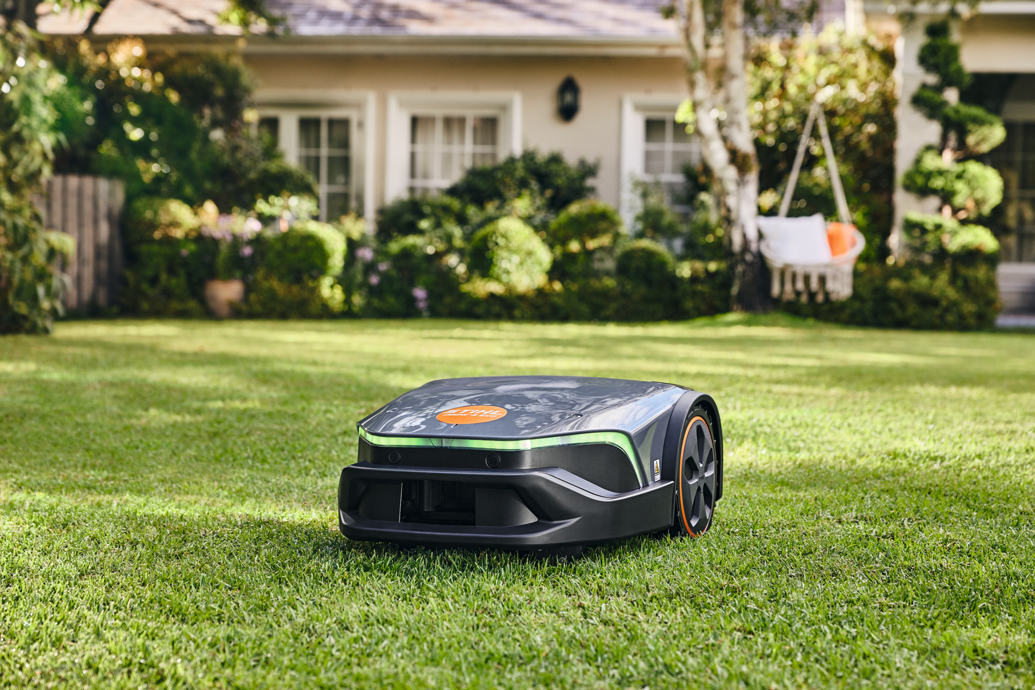 STIHL iMOW 5 EVO Mähroboter mäht Rasen vor einem Wohnhaus