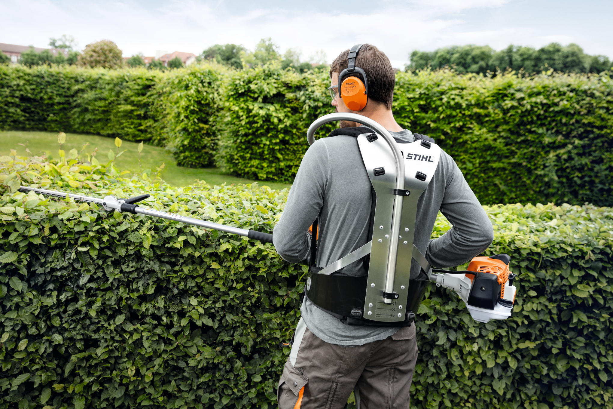 Mann verwendet STIHL Heckenschneider in einem grünen Garten