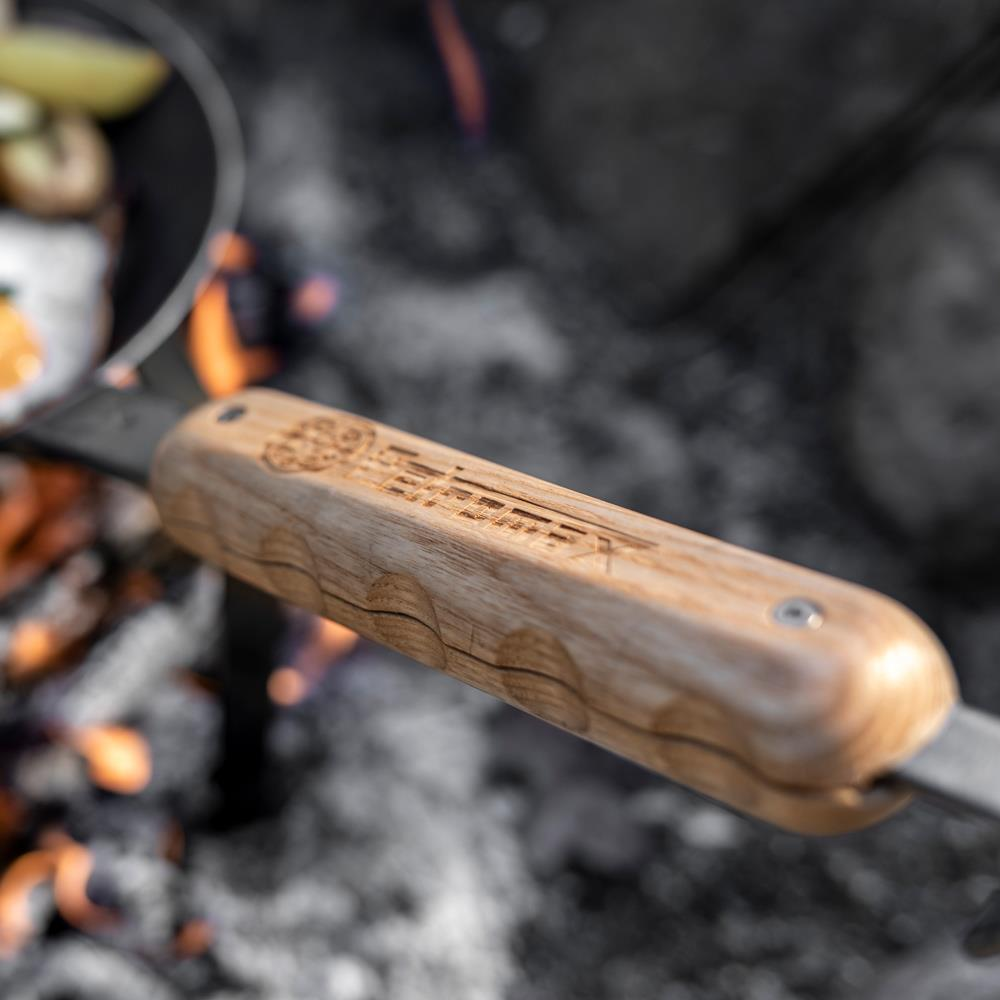Petromax Holzgriff an schmiedeeiserner Pfanne über Lagerfeuer