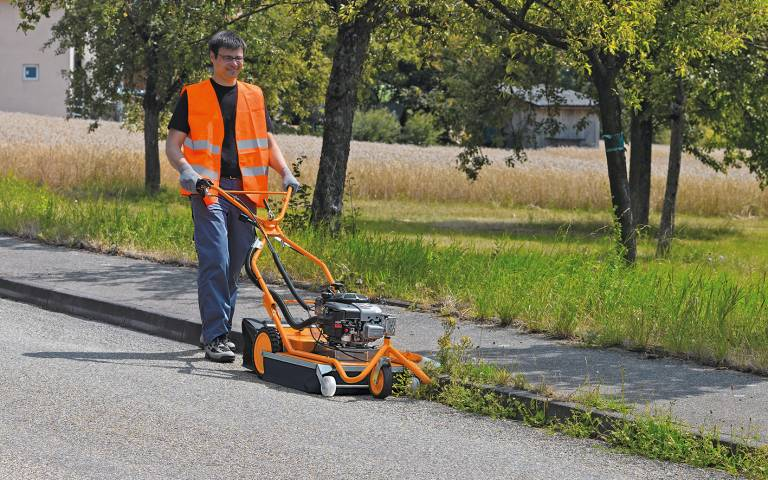 Mann verwendet AS 50 WeedHex Wildkrautentferner auf einem asphaltierten Weg