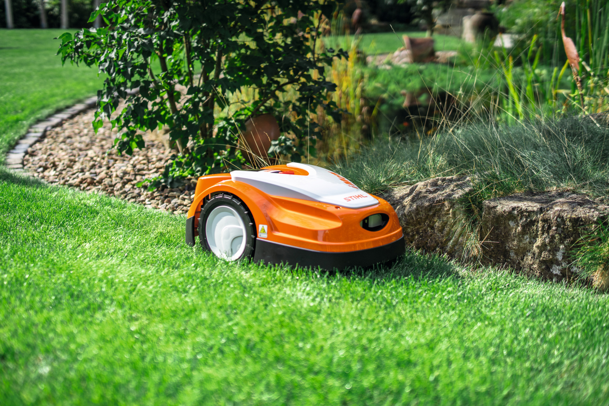 Stihl RMI 422 Mähroboter mäht autonom einen grünen Rasen in einem schönen Garten