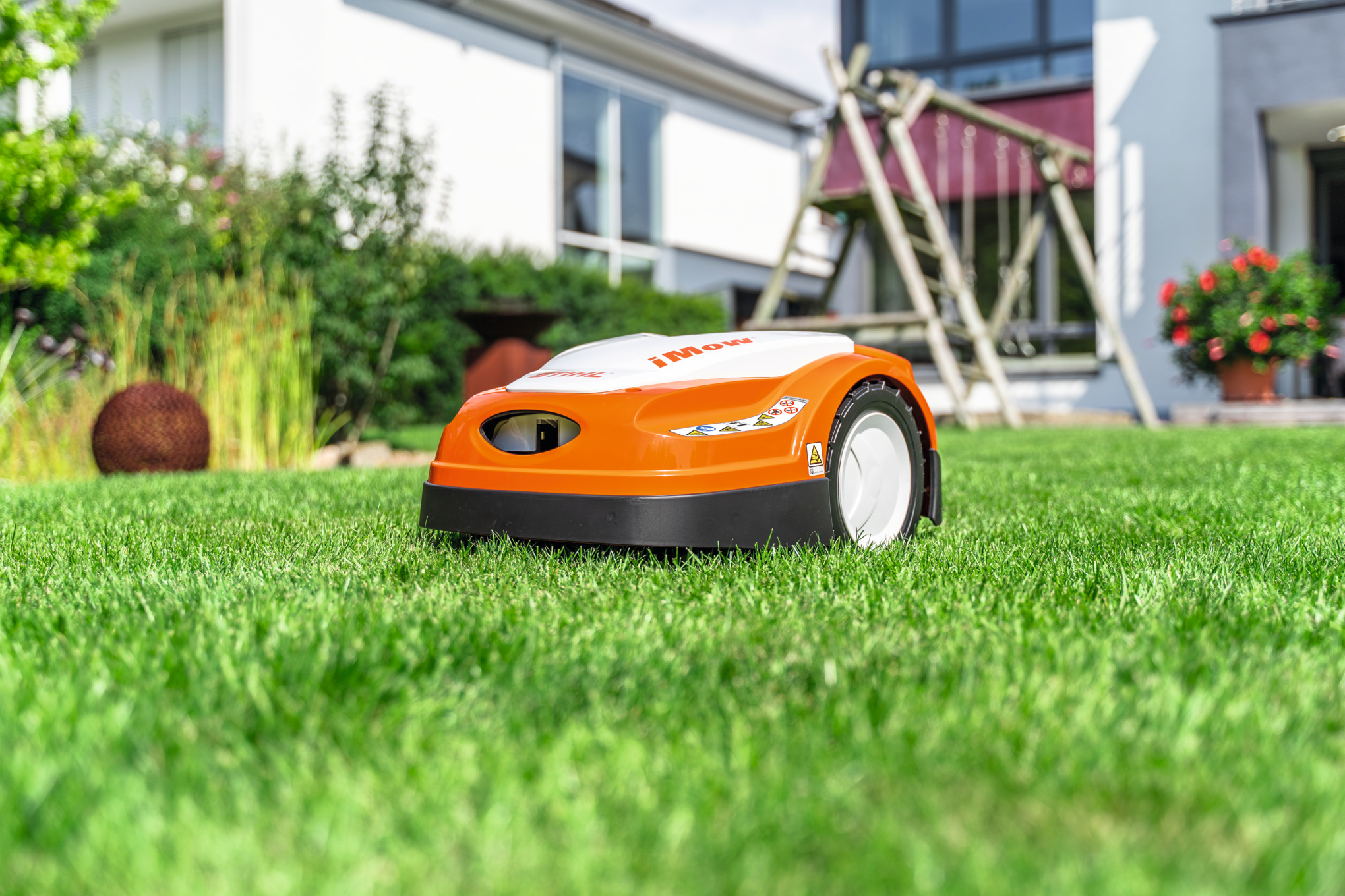 Stihl RMI 422 Mähroboter mäht Rasen vor modernem Haus und Garten
