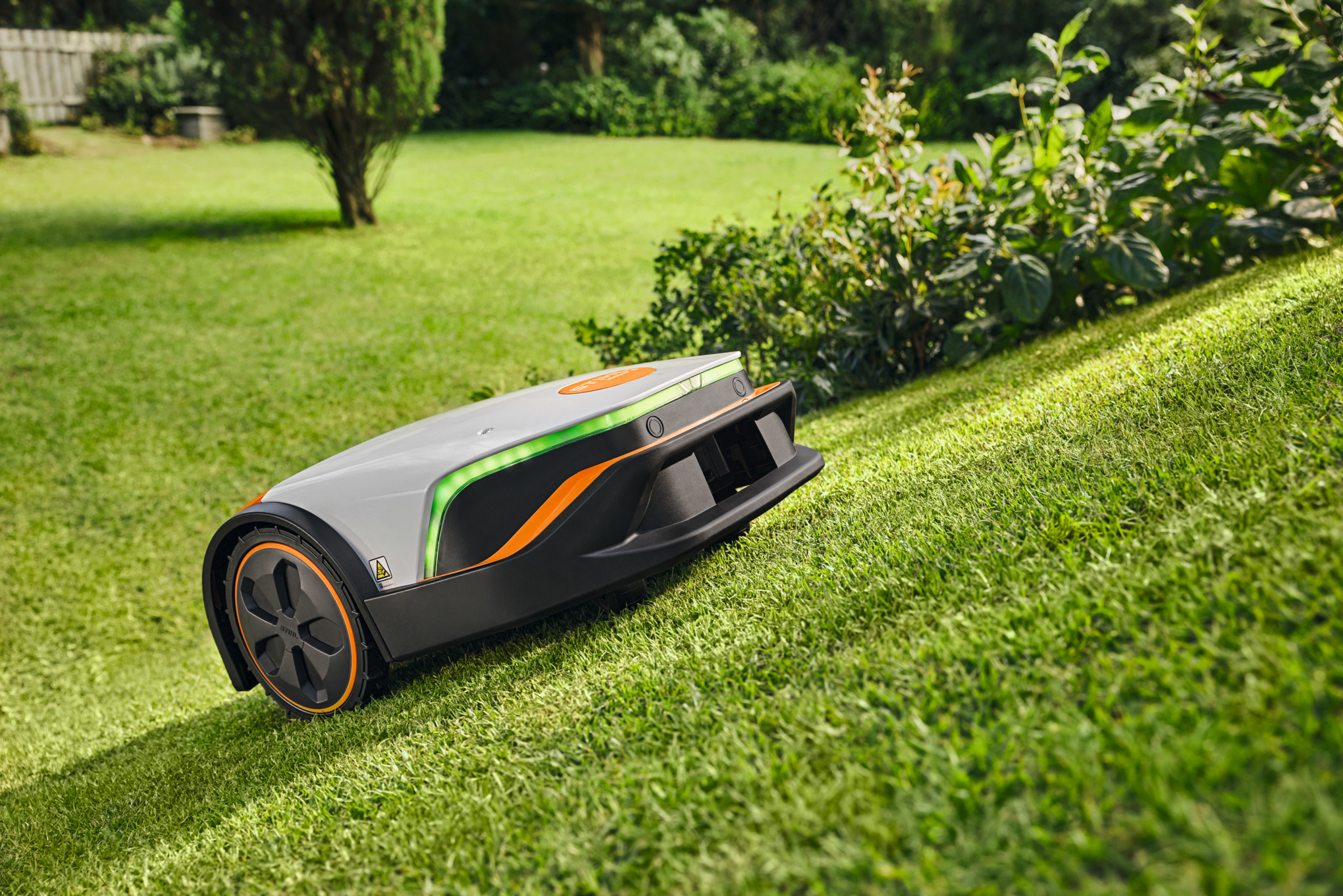 STIHL iMOW 6 Mähroboter mäht Rasen in sonnigem Garten