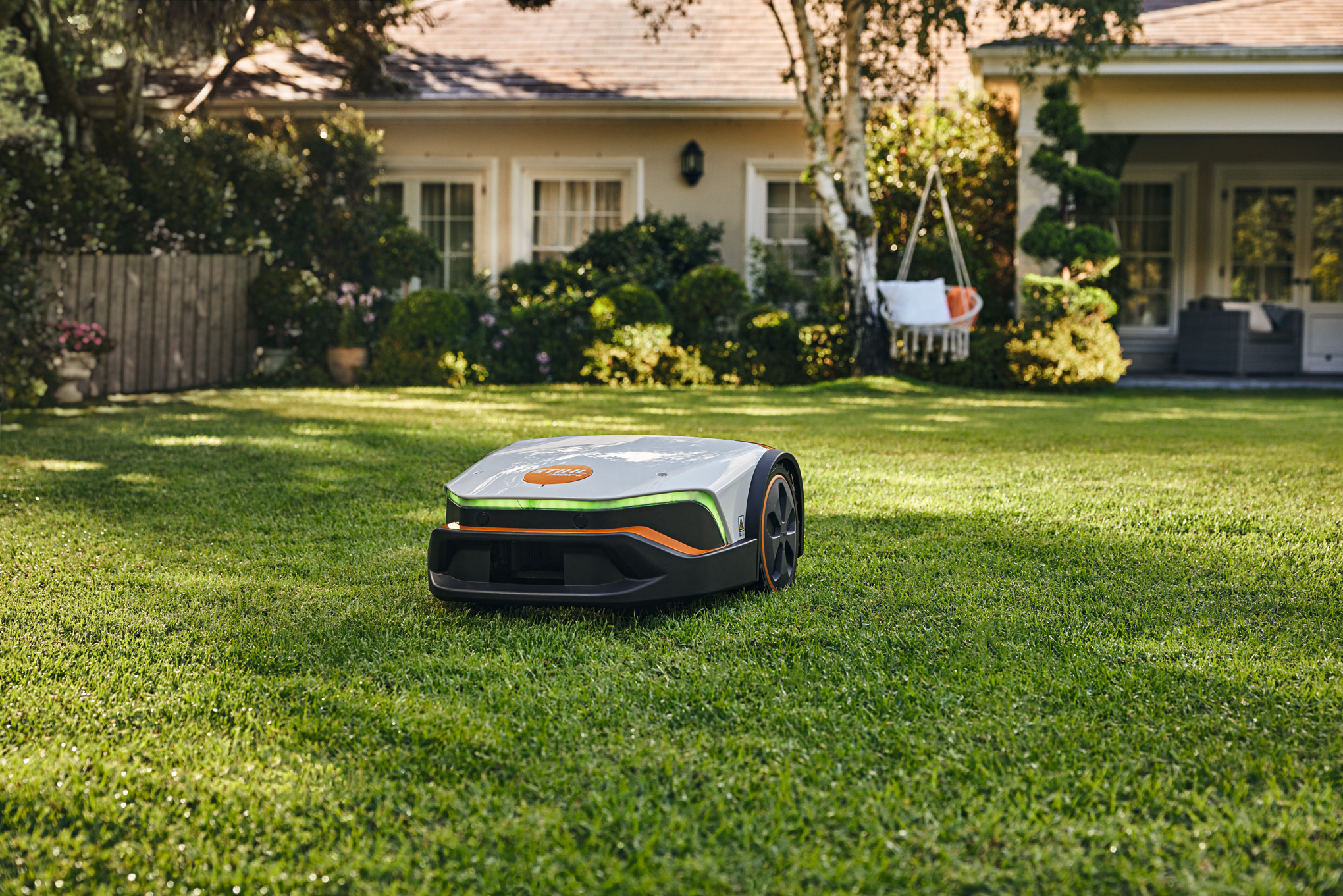 STIHL iMOW 6 Mähroboter mäht Rasen vor einem Einfamilienhaus mit Garten