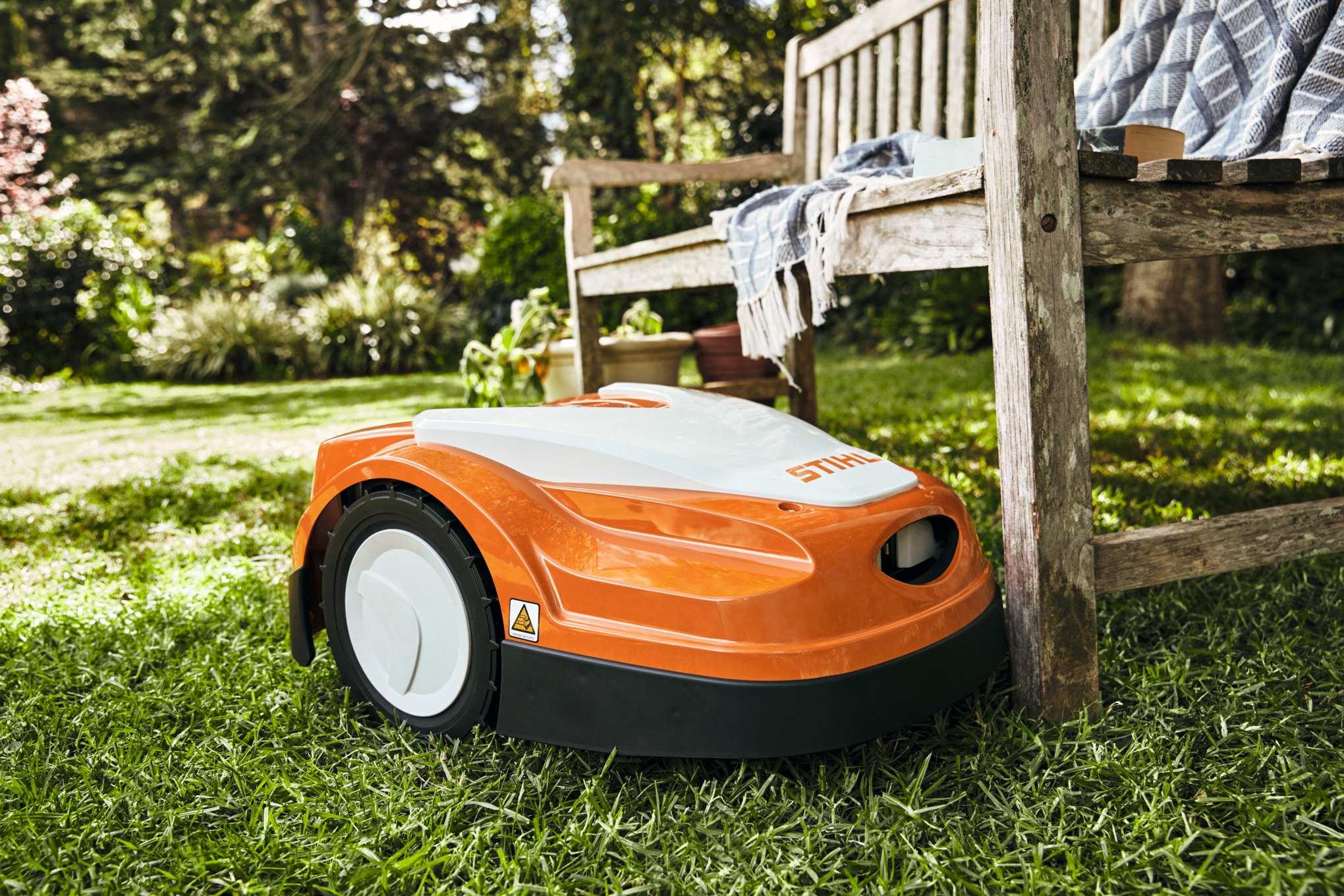 Stihl RMI 422 P Mähroboter auf grünem Rasen neben Holzgartenstuhl