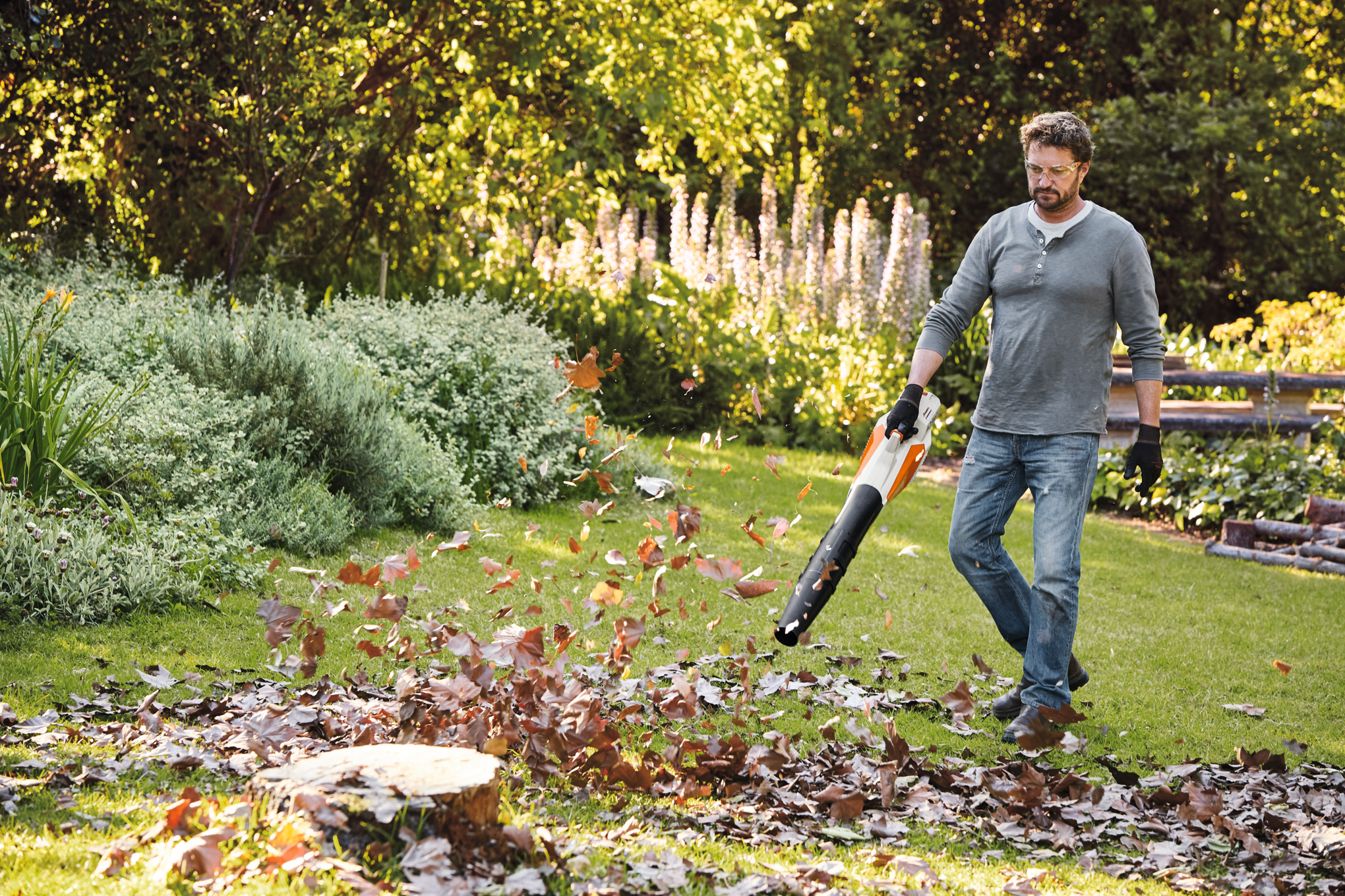 Mann verwendet Stihl BGA 57 Akku-Blasgerät im Garten zur Laubbeseitigung