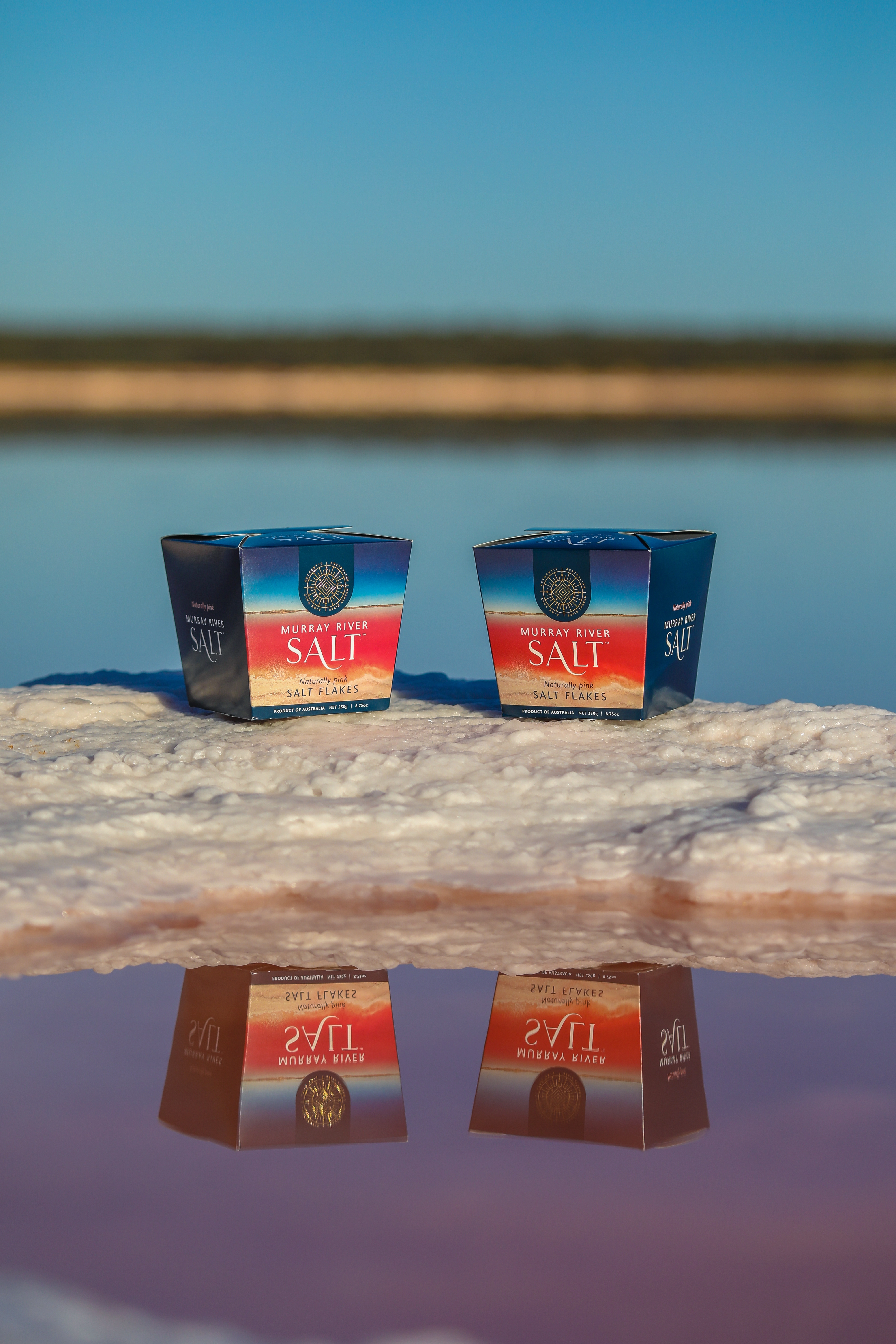 Zwei Packungen Murray River Salt auf salziger Oberfläche vor Wasser und blauem Himmel