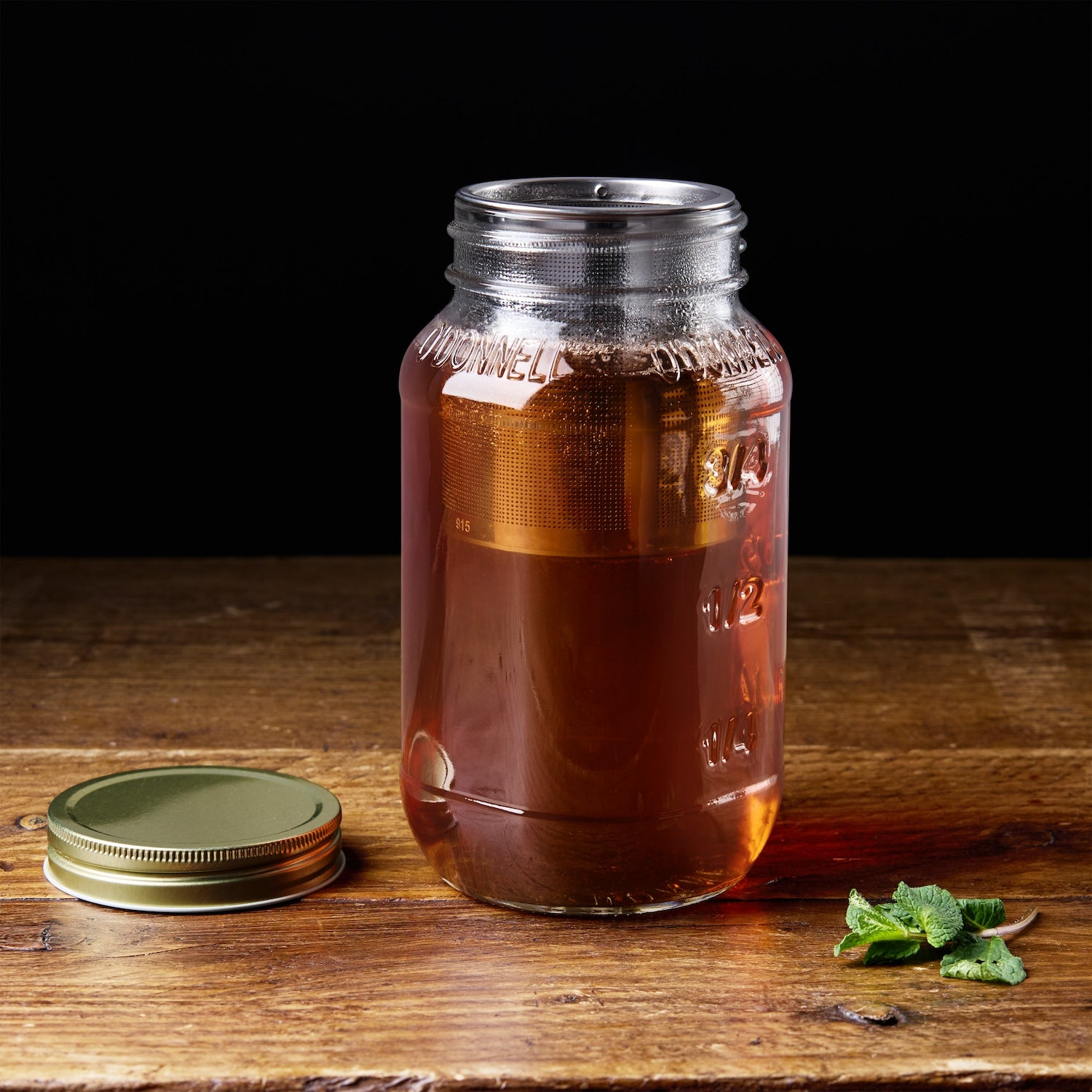 O'Donnell Mason Jar mit Teesieb und frischen Minzblättern auf Holztisch